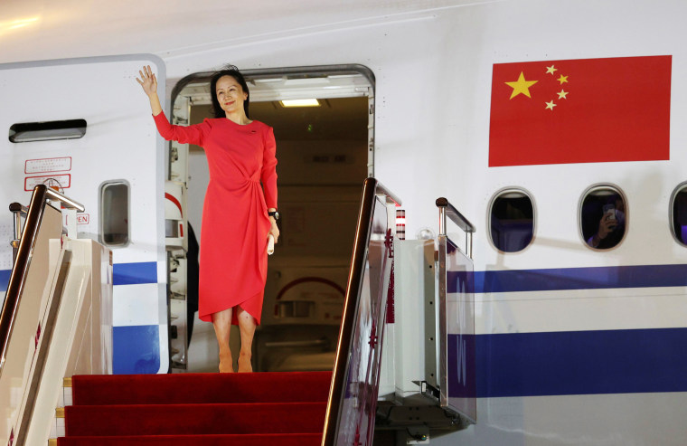 Image: Meng waves as she steps out of a airplane at Shenzhen Baoan International Airport in Shenzhen