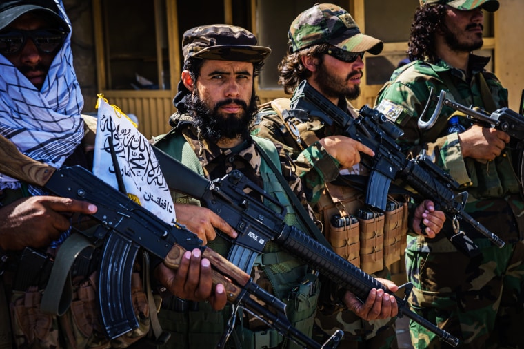 Taliban fighters line up to show off their weapons as they control access to the Abbey Gate and make Afghans with travel documents wait in Kabul, Afghanistan, on Aug. 25, 2021.