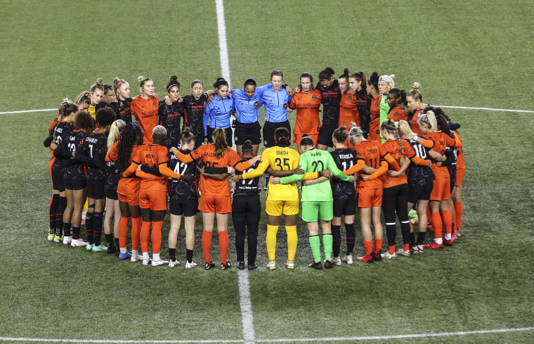 Image: Portland Thorns and Houston Dash players, along with referees, gather at midfield, in demonstration of solidarity with two former NWSL players