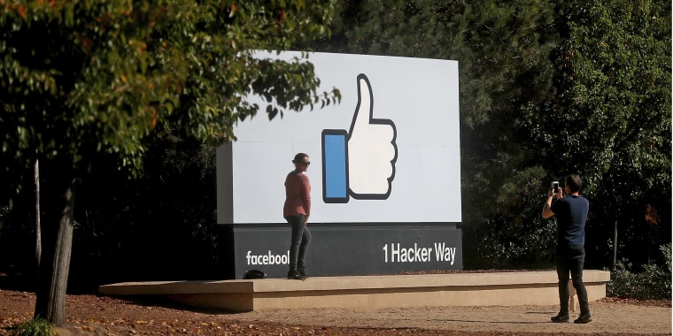 A woman poses for a photo in front of a sign at Facebook headquarters in Menlo Park, Calif., in 2017.