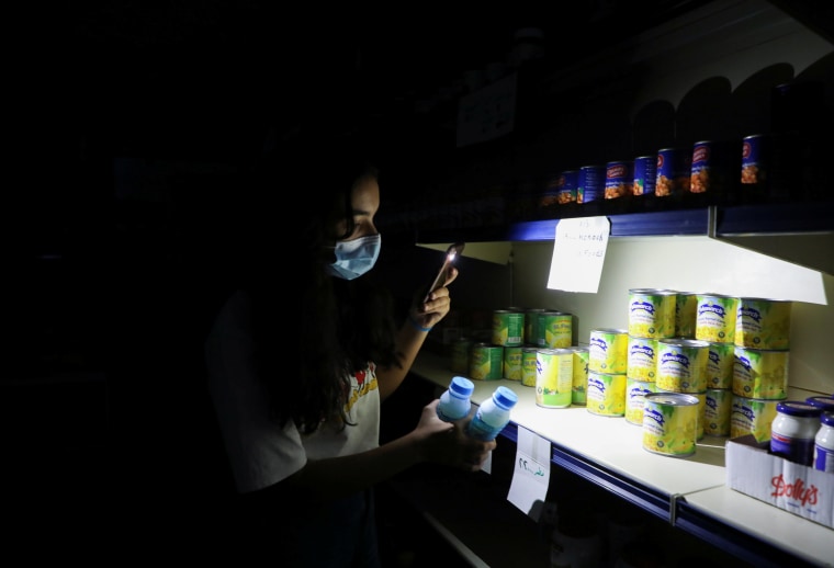 Image: A customer uses her phone's torch light in a grocery store during a power cut near Bhamdoun