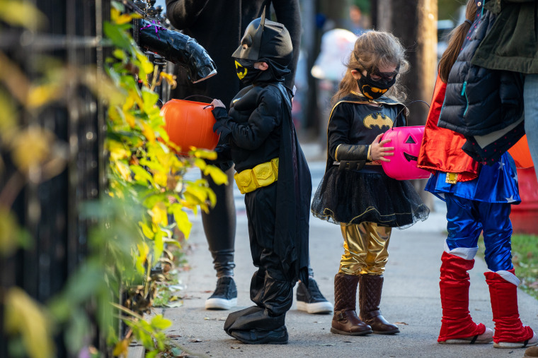 Children receive treats by candy chutes while trick-or-treating for Halloween in the Bronx, N.Y., on Oct. 31, 2020.