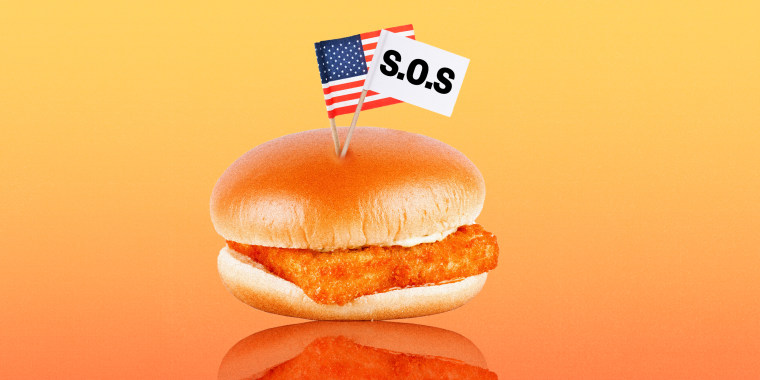 Photo illustration: A fish burger with two small paper flags, one is an American flag and the other is a white flag that reads,\"S.O.S.\"
