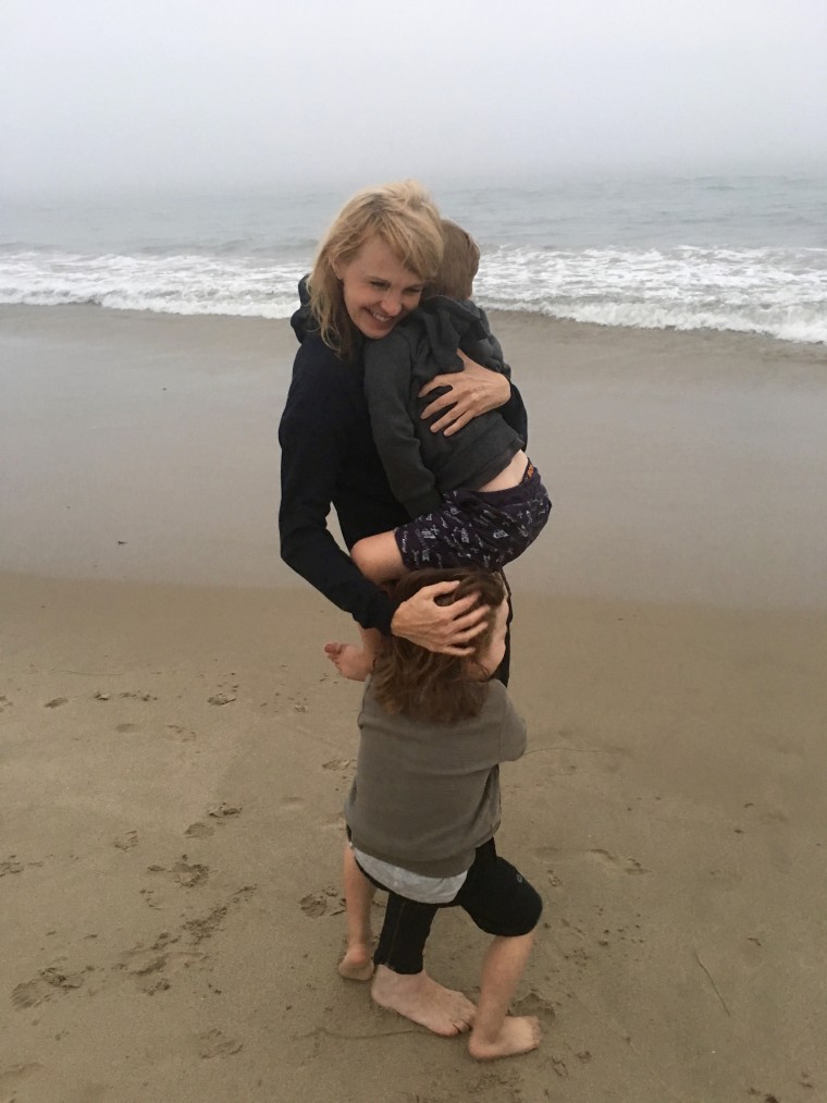 Kathryn Morris hugs her twin sons on the beach.