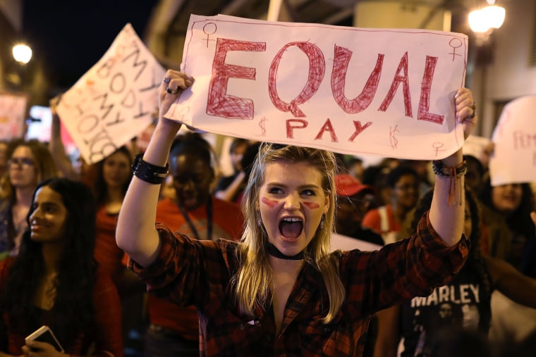 Image: A protester holds a sign that readings "Equal Pay"