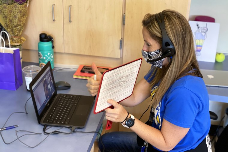 Image: Nikki Musser, an education assistant, monitors first graders attending class at Witch Hazel Elementary remotely. The school operated on a hybrid schedule last year. "Everyone here is just trying to do the best they can," she said.