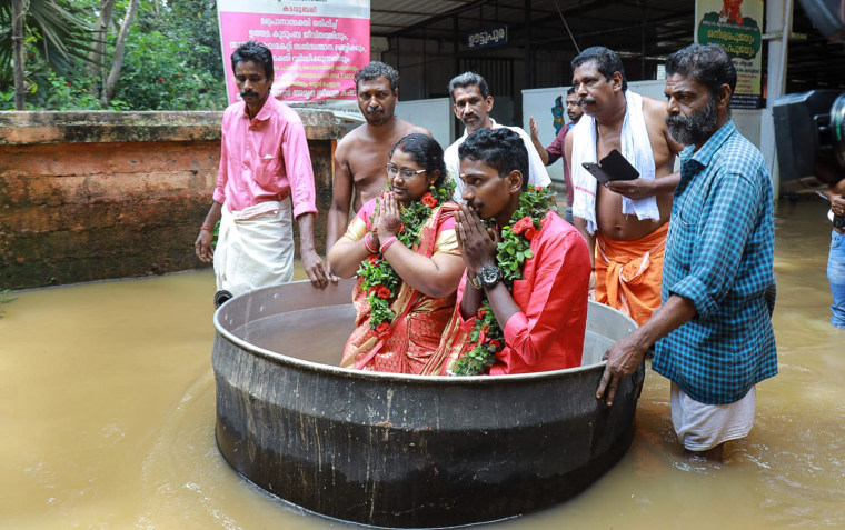 Akash and Aishwarya, an Indian couple who arrived for their wedding in unusual style after sailing through the flooded streets of their town in a cooking pot, Kerala state, India.