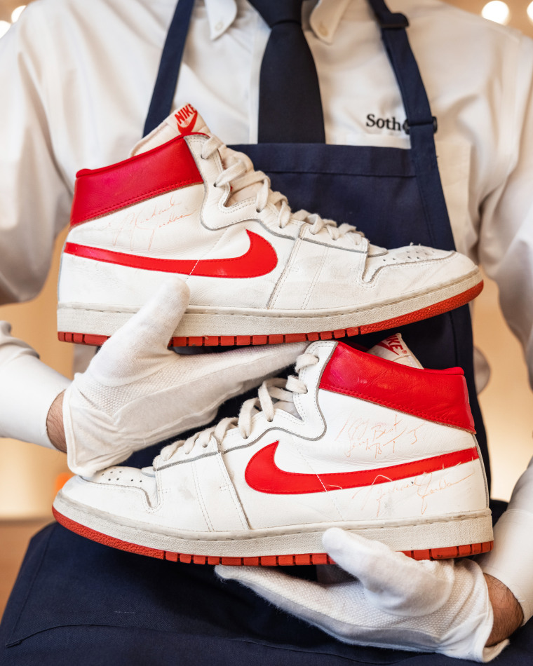 A Sotheby's employee holds the pair of Michael Jordan's Nike Air Ships from 1984 that sold for $1.472 million at auction.