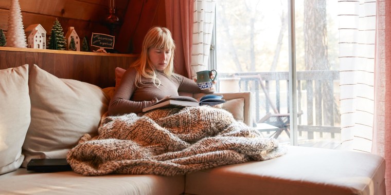 Woman reading book on sofa at home