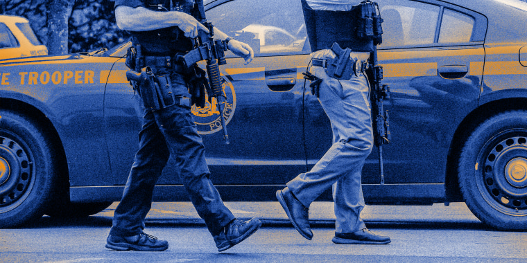 Image: Close-up image of two armed police officers walking.