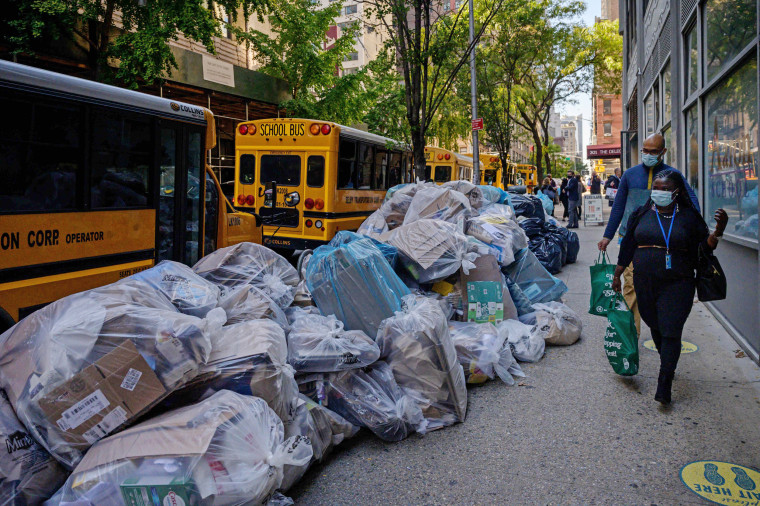 Pedestrians pass by trash bags piled on a street in New York on Oct. 28, 2021.