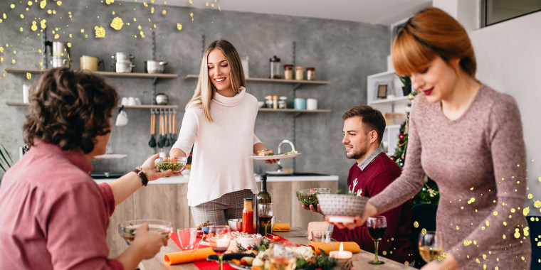 Group of friends cleaning dining table after christmas diner together