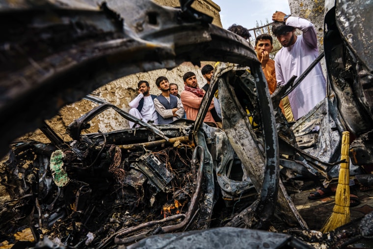 Image: Relatives and neighbors of the Ahmadi family gathered around the incinerated husk of a vehicle in Kabul, Afghanistan, on August 30, 2021.
