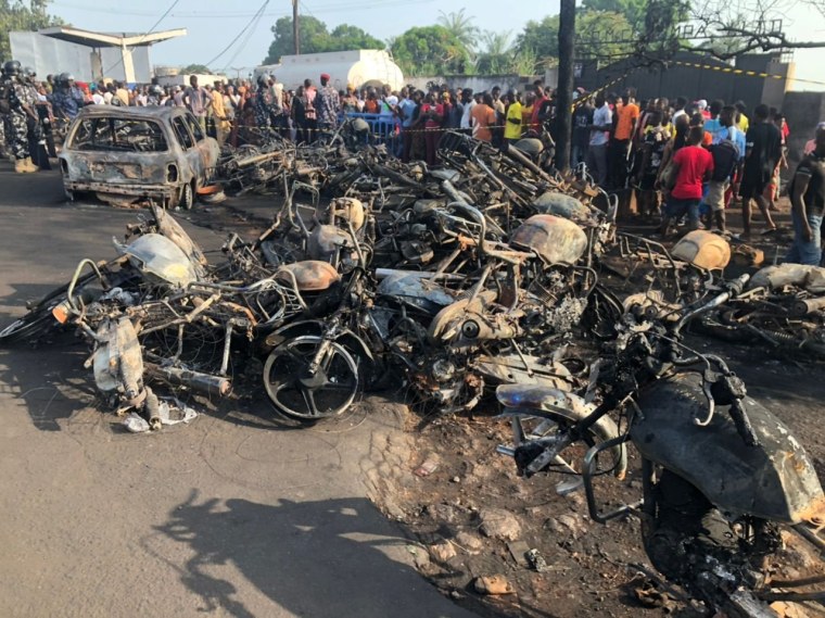 Image: People watch burnt car and motorcycles after a fuel tanker explosion in Freetown