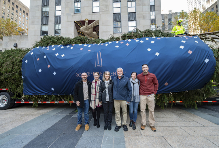Julie and Devon Price, center, pose with family in front of the wrapped 79-foot tall, 12-ton Norway spruce from Elkton, Maryland, on Nov. 13. They donated the tree to serve as the 2021 Rockefeller Center Christmas tree.