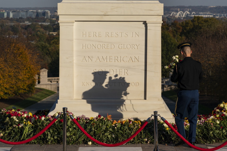 A soldier with the 3rd U.S. Infantry Regiment, known as \"The Old Guard,\" moves flowers during a centennial commemoration event at the Tomb of the Unknown Soldier, in Arlington National Cemetery.