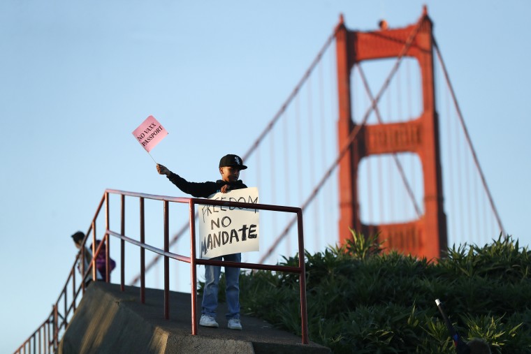 A young boy waves a sign during a rally against vaccine mandates at the Golden Gate Bridge in San Francisco on Nov. 11, 2021.