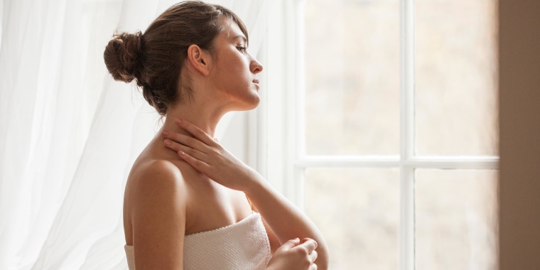 Woman putting on neck cream for skin care