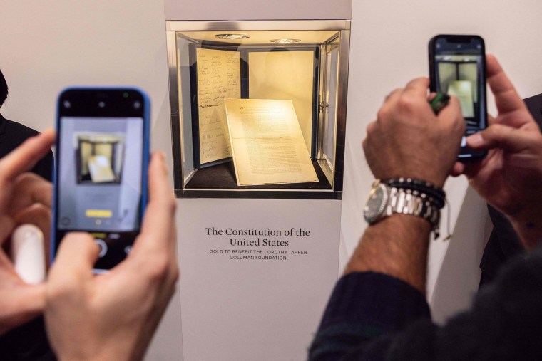 People take pictures of the first printing of the United States Constitution during an auction at Sotheby's auction house in New York on November 18, 2021. - An extremely rare original copy of the US constitution was sold on November 18, 2021 for $43 million -- a world record for a historical document at auction, Sotheby's said.