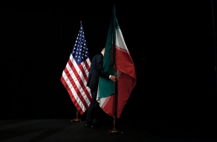 Image: A member of staff removes the Iranian flag from the stage after a group picture with foreign ministers and representatives of United States, Iran, China, Russia, Britain, Germany, France and the European Union