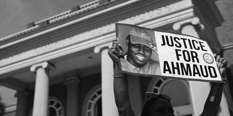 Image: A demonstrator holding a sign that reads, \"Justice for Ahmaud\"outside a courthouse.