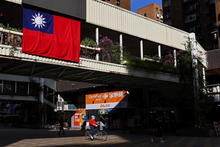Image: A man cycles past a Taiwan flag in Taipei