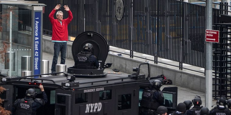 A man raises his hands after holding a gun under his chin, as he speaks with members of the NYPD outside the United Nations Headquarters in New York on Dec. 2, 2021.