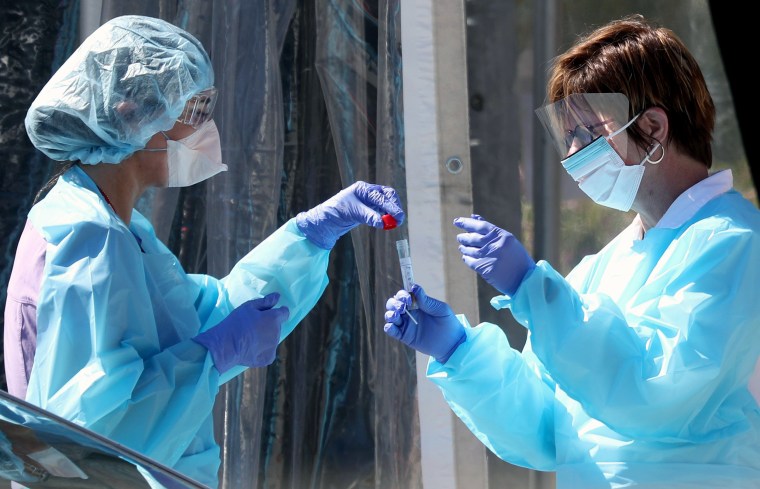 Image: Medical personnel secure a sample from a person at a drive-thru Covid-19 testing station at a Kaiser Permanente facility on March 12, 2020 in San Francisco.