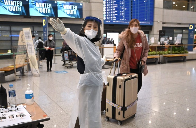 A staff member guides a traveller at the arrival hall of Incheon International Airport in South Korea on Nov. 30, 2021.