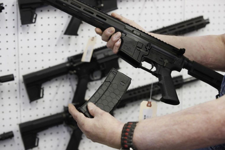 A salesperson holds a high capacity magazine for an AR-15 rifle at a store in Orem, Utah, on March 25, 2021.