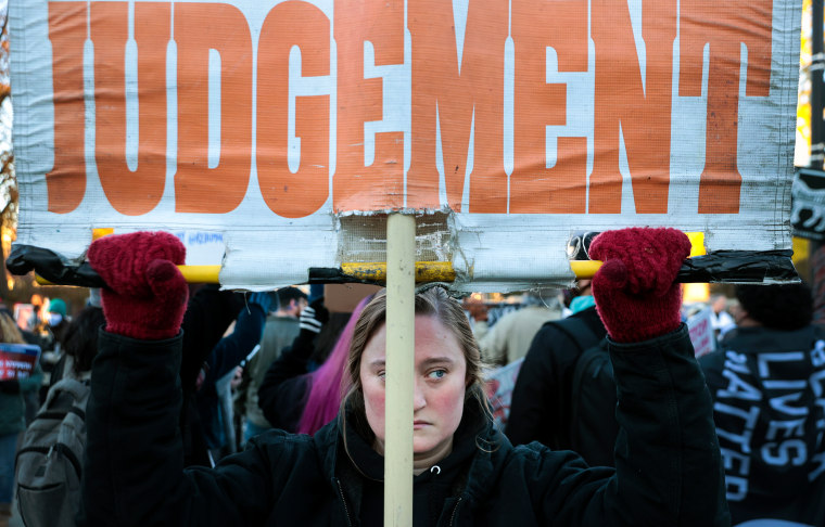 Image: A woman holding up a sign that reads,\"Judgement\".