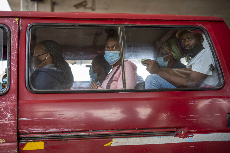 Passengers, some wearing masks, wait for their taxi to leave in Soweto, South Africa, on Thursday. 