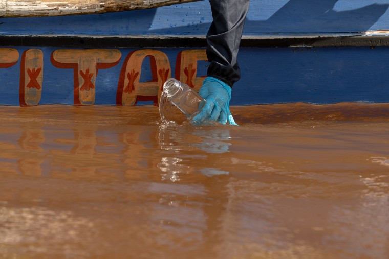 A reporter takes a water sample at the estuary of the Tuba River where the Togpon River merges.