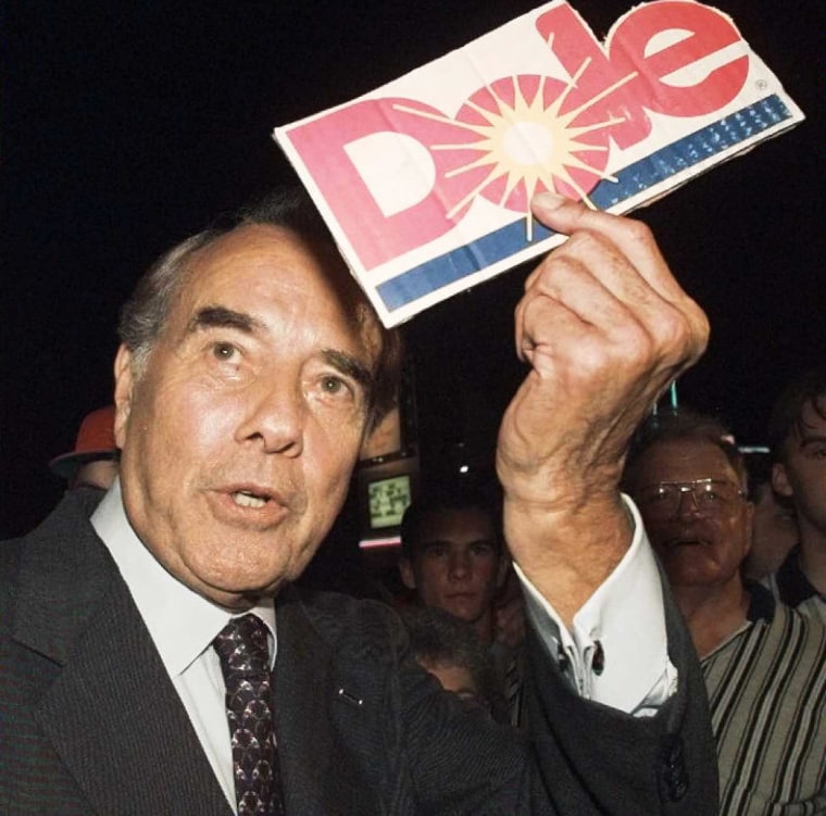 Republican presidential candidate Bob Dole holds a Dole pineapple sign given to him by a supporter outside of his hotel in Branson, Mo., on June 12, 1996.