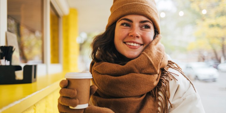 Woman in winter hat and scarf holding coffee cup