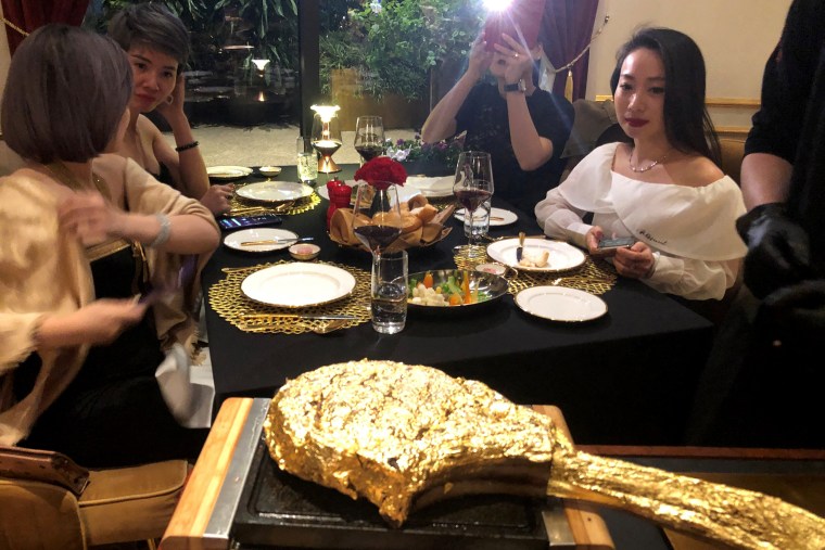 Image: A customer takes pictures of a gold leaf-coated steak, at a Dolce By Wyndham Hanoi Golden Lake hotel, in Hanoi