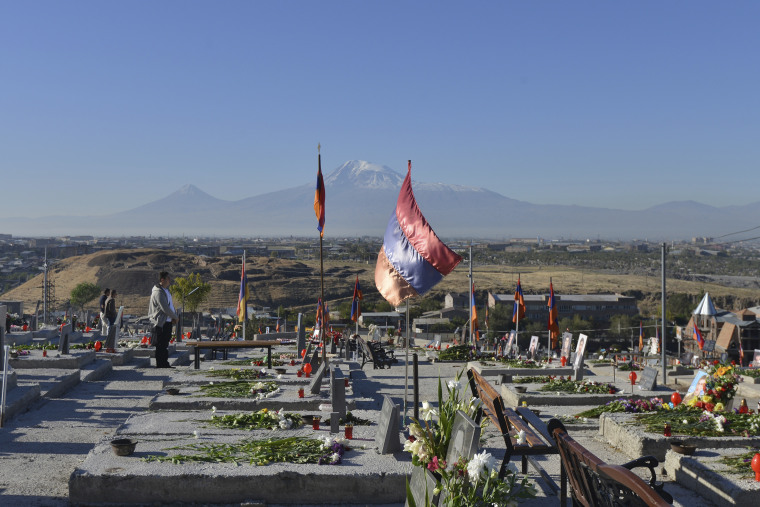 Relatives visit a military cemetery with the graves of Armenian soldiers killed during the fighting over Nagorno-Karabakh in 2020, outside Yerevan, Armenia, Sept. 27, 2021.