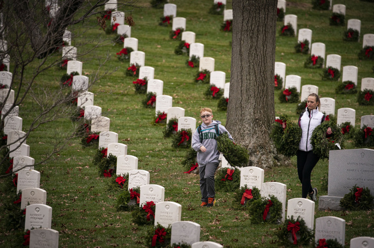 People carry wreaths to place on tombstones at Arlington National Cemetery, on December 18, 2021 in Arlington, Virginia.