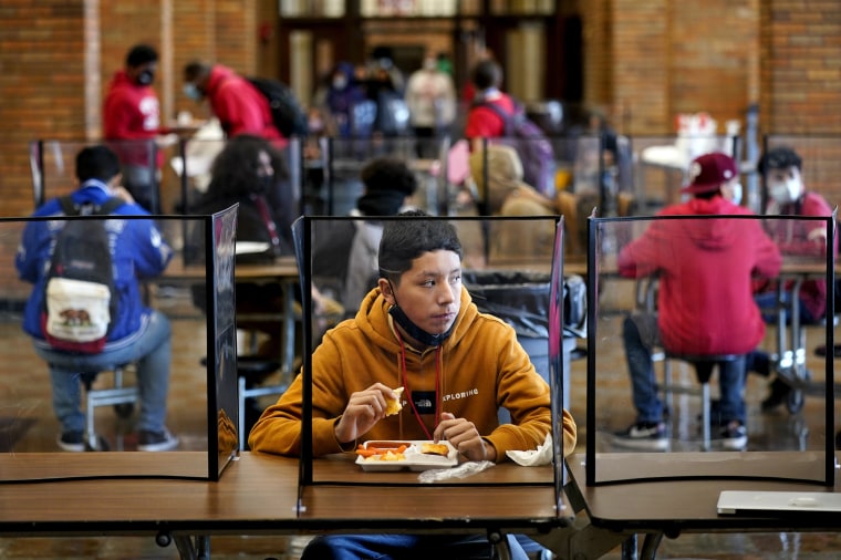 Image: Students eat lunch separated by plastic dividers at Wyandotte County High School in Kansas City, Kan., on March 31, 2021.