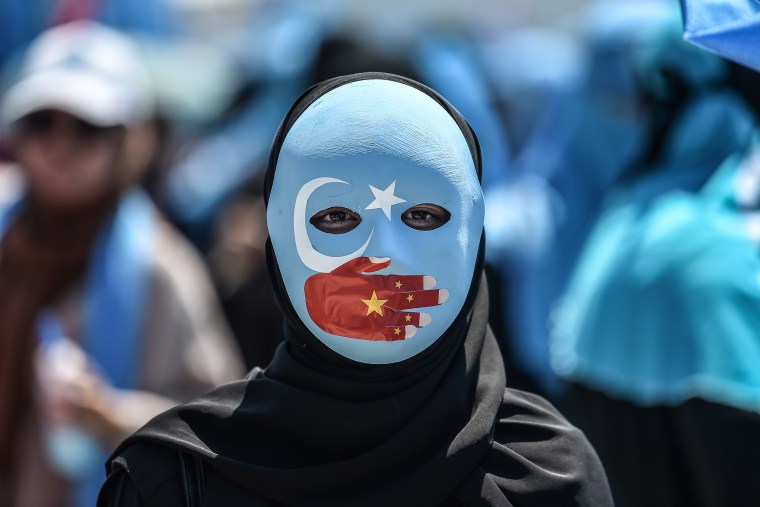 A demonstrator wearing a mask painted with the colors of the flag of East Turkestan and a hand bearing the colors of the Chinese flag attends a protest to denounce China's treatment of ethnic Uighur Muslims, in Istanbul July 5, 2018.