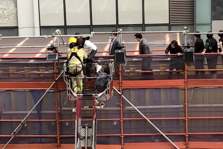 Firefighters use a crane to rescue people lined up on a roof after a fire broke out at the World Trade Centre in Hong Kong, on Dec. 15, 2021