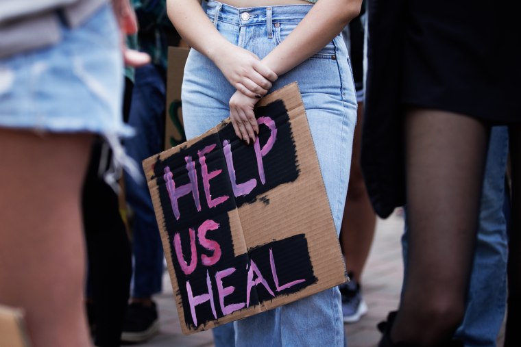 A Santa Clara University senior holds a sign during a rally demanding better counseling and mental health services for all students on Dec. 2, 2021, in Santa Clara, Calif.
