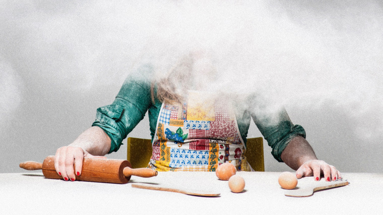 Image: A woman with baking tools and ingredients covered by a cloud of white flour.