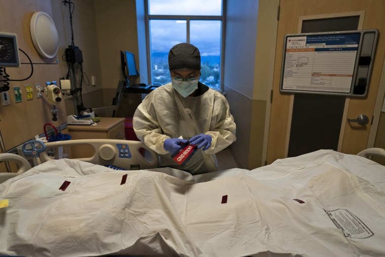 A registered nurse attaches a \"COVID Patient\" sticker on the body bag of a patient who died of coronavirus at Providence Holy Cross Medical Center in Los Angeles on Dec. 14, 2021.