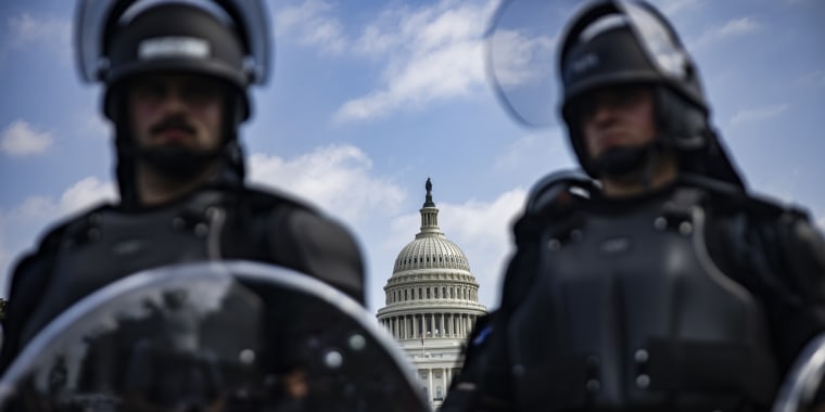 Image: Two officers stand guard with the U.S. Capitol in the background.