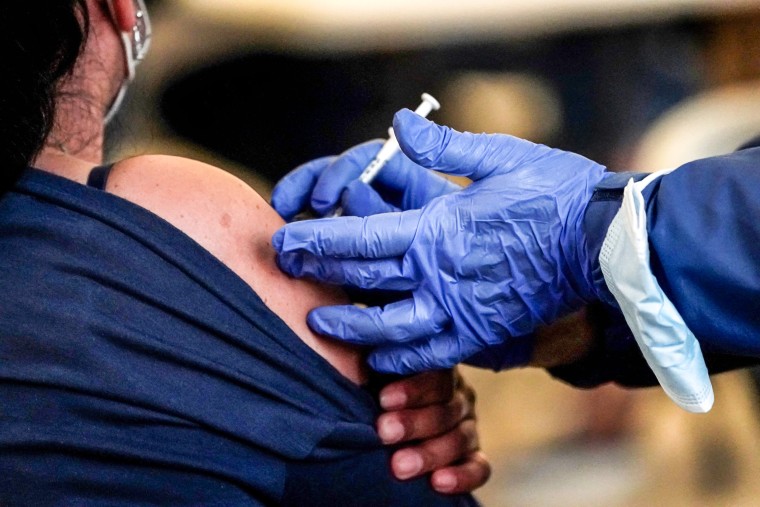 A Los Angeles County Department of Public Health worker administers a dose of a Covid-19 vaccine at a pop-up clinic at Los Angeles International Airport on Dec. 22, 2021.
