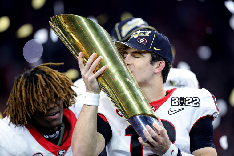 Stetson Bennett #13 of the Georgia Bulldogs celebrates with the National Championship trophy after the Georgia Bulldogs defeated the Alabama Crimson Tide 33-18 during the 2022 CFP National Championship Game at Lucas Oil Stadium on January 10, 2022 in Indi