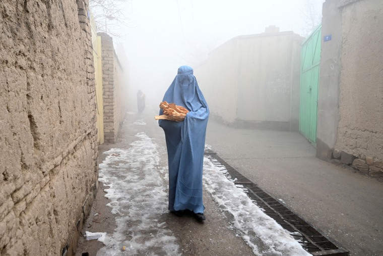 Image: A woman in a burqa walks home after receiving free bread in Kabul on Jan. 18, 2022.