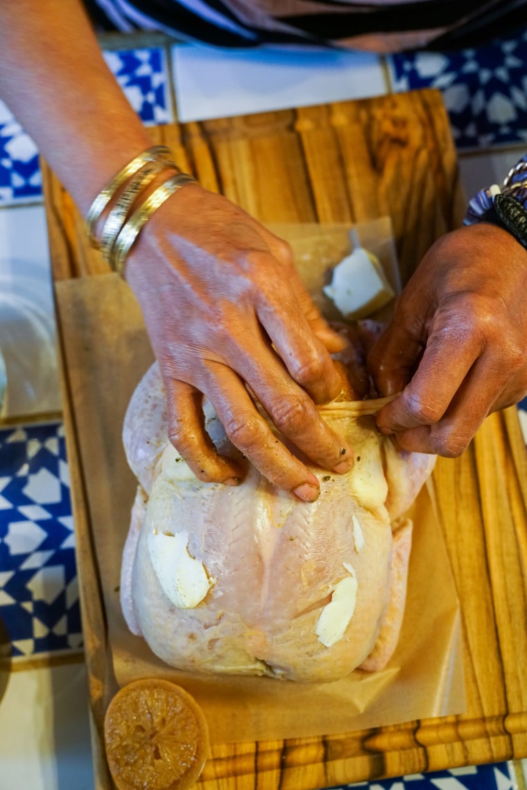 Harris rubs butter under the skin of the chicken.