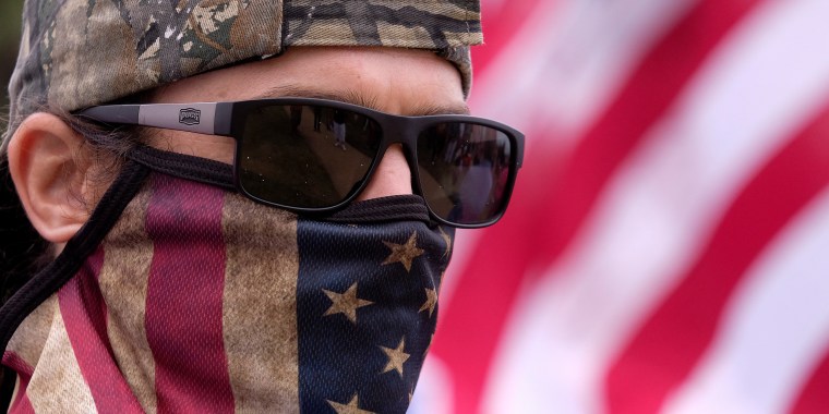 Image: An anti-vaccination protester wearing a face mask with American flag takes part in a rally against Covid-19 vaccine mandates.